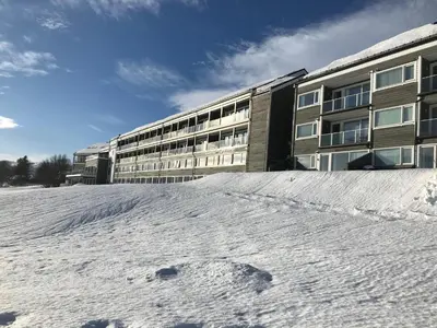 a snow covered parking lot in front of a building at Geilo Superior leilighet in Geilo