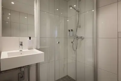 a white bathroom with a shower and a sink at Scandic Victoria Lillehammer in Lillehammer