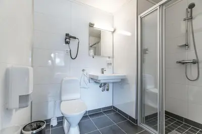 a bathroom with a toilet and a sink and a shower at Almaas Hotell Stord AS in Stord