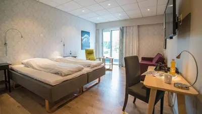 a bedroom with a bed and a table and a desk at Almaas Hotell Stord AS in Stord