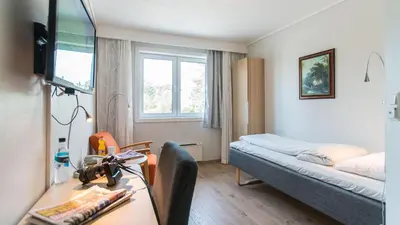 a small room with a bed and a desk with a desk at Almaas Hotell Stord AS in Stord