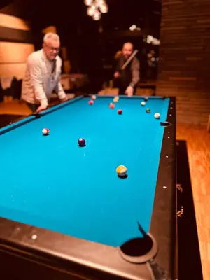 two men playing a game of pool on a pool table at Honne Hotell in Biri