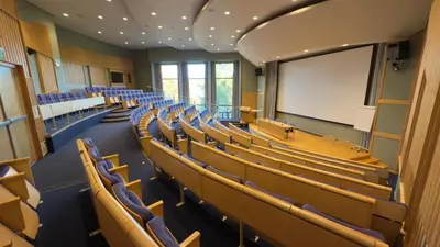 an empty lecture hall with chairs and a white screen at Honne Hotell in Biri