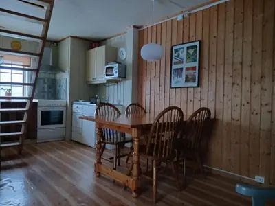 a kitchen and dining room with a wooden table and chairs at Bustad Hyttetun in Skåbu