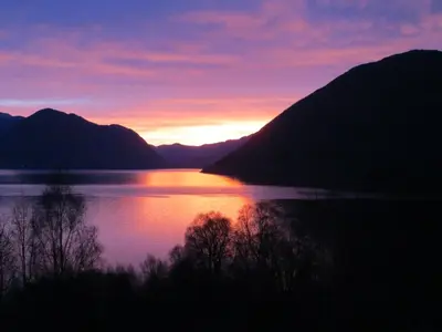 a sunset over a body of water with mountains at Cosy chalet, 100m2 with fjordview! in Lauvstad