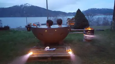 a couple of people in a bathtub with a view of a lake at Tiny house with Fjordview! in Lauvstad