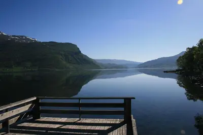 a bench sitting on a dock next to a lake at Bøflaten Camping AS in Vang I Valdres