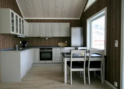 a kitchen with white cabinets and a table and chairs at Bøflaten Camping AS in Vang I Valdres