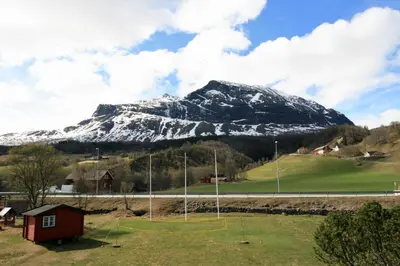 a snow covered mountain with a red house in front at Bøflaten Camping AS in Vang I Valdres
