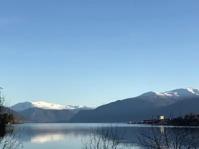 a view of a lake with snow covered mountains at Villa Holmen 2 - Ground floor apartment in Balestrand