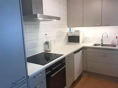 a white kitchen with a sink and a microwave at Villa Holmen 2 - Ground floor apartment in Balestrand