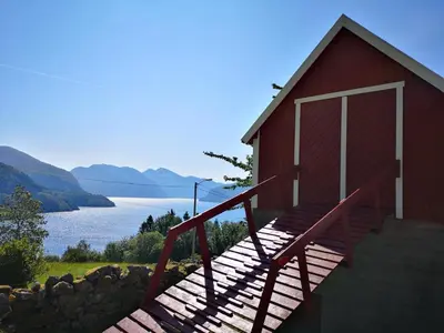 a red building with a staircase next to a lake at Fjords view in Sjøholt