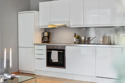 a white kitchen with white cabinets and a refrigerator at BJØRVIKA APARTMENTS, Solsiden Area, Trondheim city center in Trondheim