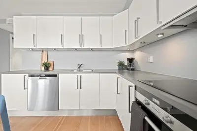 a white kitchen with white cabinets and a sink at BJØRVIKA APARTMENTS, Solsiden Area, Trondheim city center in Trondheim