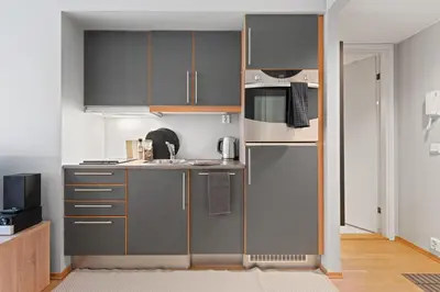 a small kitchen with gray cabinets and a microwave at BJØRVIKA APARTMENTS, Solsiden Area, Trondheim city center in Trondheim