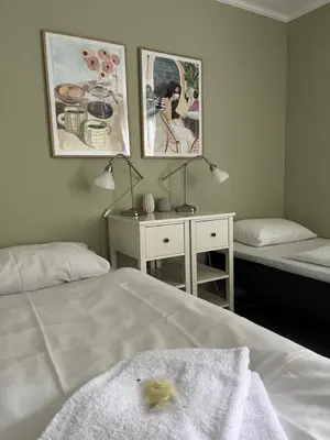 a bedroom with two beds and a desk with a towel at Klostergården Bed & Breakfast in Tautra