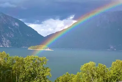 a rainbow over a lake with trees and mountains at Sunndalsfjord Cottages Fredsvik Meisalstranda 455,506 og 508 in Sunndalsøra