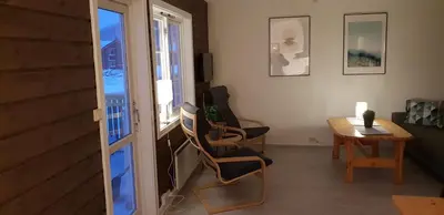 a living room with a table and chairs and a window at Oppdal Alpintun Stølen ski in - ski out in Oppdal
