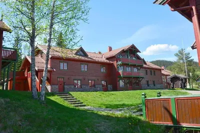 a large red building with a fence in front of it at Sjumilskogen in Trysil