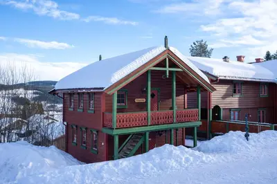 a large wooden house with snow on the ground at Sjumilskogen in Trysil