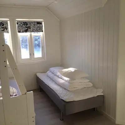 a small room with a bed and two windows at Havbris in Bremnes