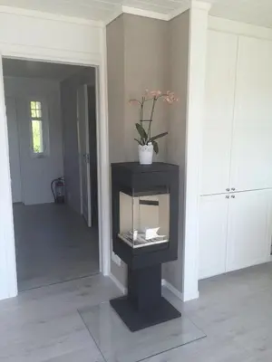 a room with a black fireplace with a plant in it at Havbris in Bremnes