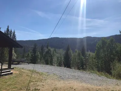 a view of a hill with trees and the sun at Sjoaasen Hytte in Tuddal