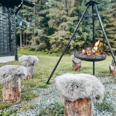 a fire pit in a field with some logs at Sjoaasen Hytte in Tuddal