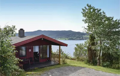 a small red cabin with a view of a lake at Lovely Home In Sandvoll With Wifi in Sandvoll