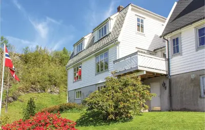 a white house with a flag in front of it at Awesome Home In Holmefjord in Holmefjord