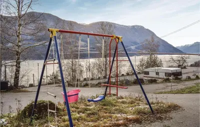 an empty swing set with a lake in the background at 3 Bedroom Lovely Home In Vallavik in Vangsbygd
