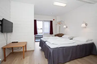two beds in a room with a table and a tv at Midttun Motell & Camping AS in Bergen