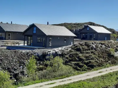 a house on a hill next to a dirt road at Atlanterhavsveien Rorbuer in Averoy