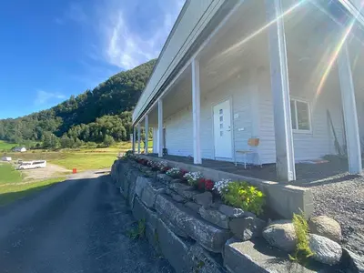 a white house with a stone retaining wall next to it at Botnen Camping in Botnen