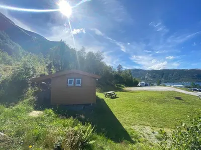 a small house in a field with the sun in the sky at Botnen Camping in Botnen