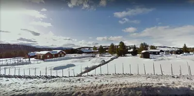 a snow covered field with a fence and houses at Rondaplassen in Kvam