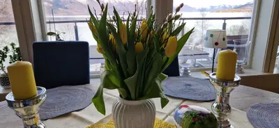 a table with a vase with yellow flowers in it at Frydenlund in Balestrand