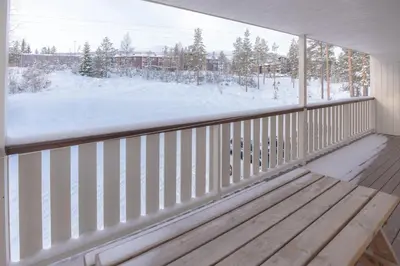 a balcony with a wooden bench and a snow covered yard at Fjelltun 8-sengs in Trysil