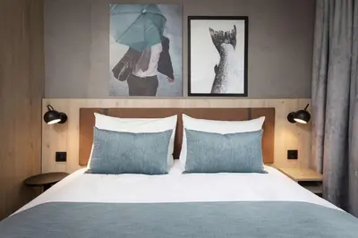 a bedroom with a bed with two blue pillows at Scandic Kokstad in Bergen
