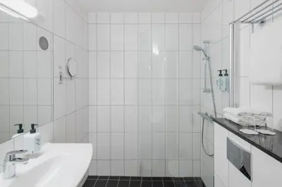a white bathroom with a shower and a sink at Scandic Kokstad in Bergen