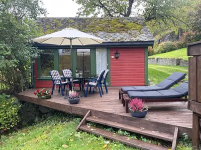 a wooden deck with a table and chairs and an umbrella at Ingrids Apartments in Eidfjord