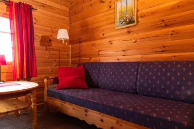 a couch in a room with a wooden wall at Hakkesetstølen Fjellstugu in Geilo