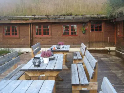 a picnic table with benches in front of a building at Hakkesetstølen Fjellstugu in Geilo