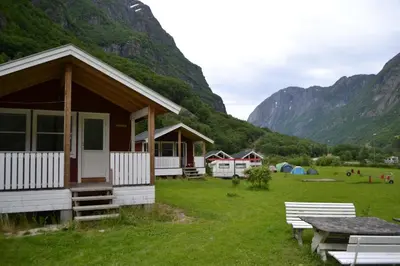 a cabin in a field with mountains in the background at Gudvangen Camping in Gudvangen
