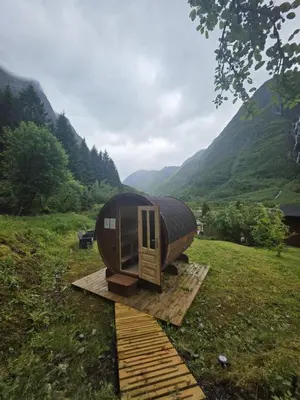 a cabin in a field with mountains in the background at Gudvangen Camping in Gudvangen