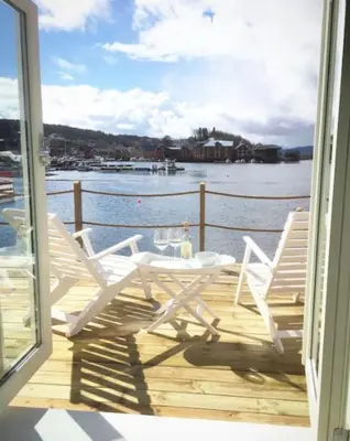 a table and chairs on a deck with a view of the water at The Boathouse in Råkvåg