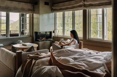 a woman sitting in a chair in a room with a fireplace at Storfjord Hotel in Skodje