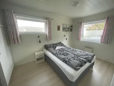a small bedroom with a bed and two windows at Åndalsnes Apartments - Luxury Stay in Åndalsnes