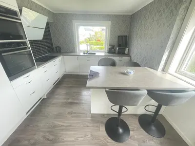 a kitchen with white cabinets and a table and chairs at Åndalsnes Apartments - Luxury Stay in Åndalsnes
