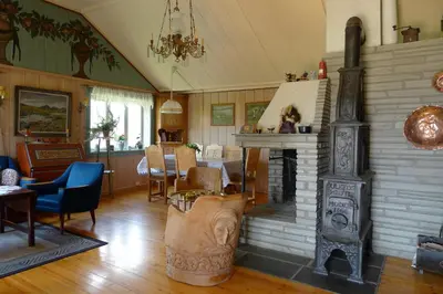 a living room with a fireplace and a dining room at Romenstad Hytter in Rendalen